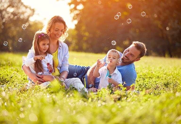 parents and children playing in the park with bubbles